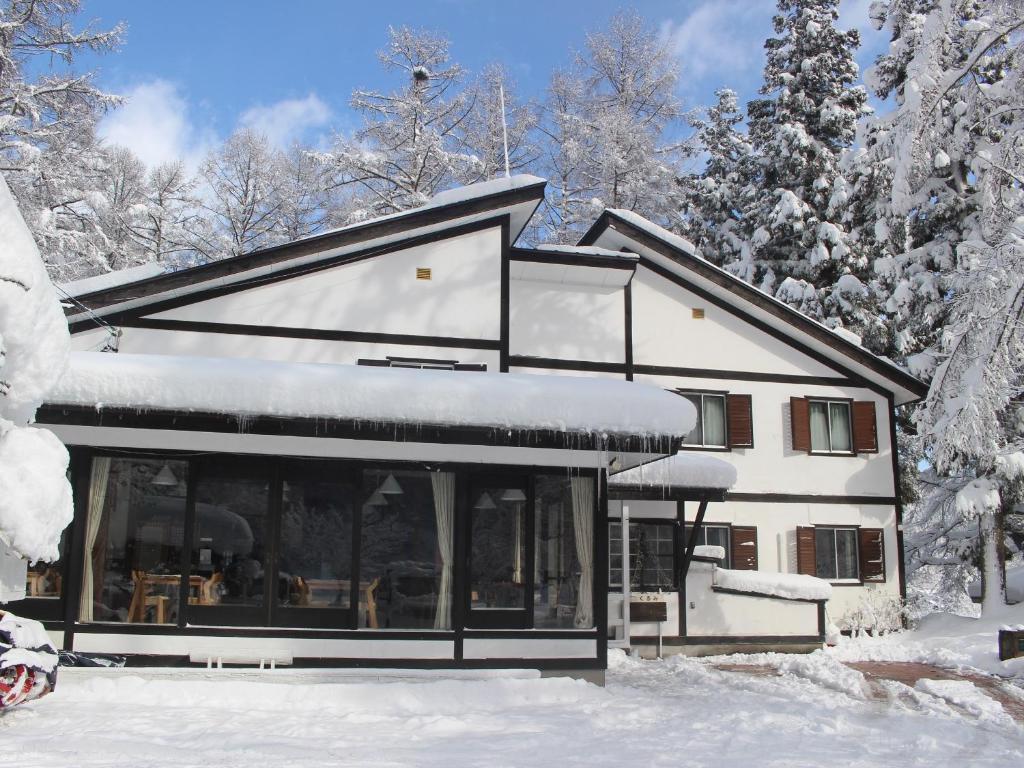 白马村白马五龙久留美酒店的雪中的房子,有雪覆盖的树木