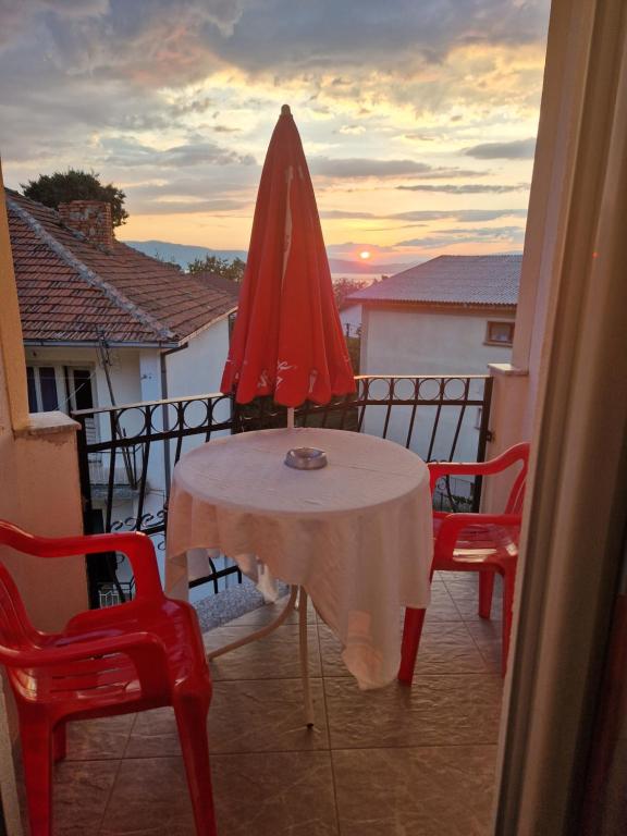 佩斯塔尼Apartments Picioski的阳台上的一张桌子和一把红色遮阳伞
