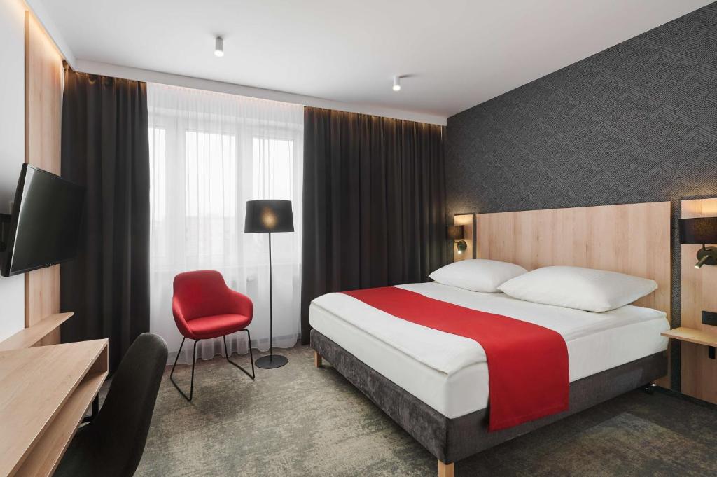 热舒夫Best Western Plus Hotel Rzeszow City Center的酒店客房,配有一张床和一张红色椅子