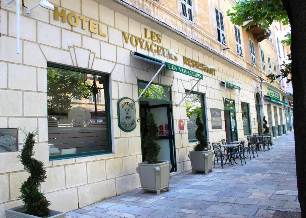 巴斯蒂亚Hôtel Les Voyageurs的一座配有桌椅的建筑前的商店