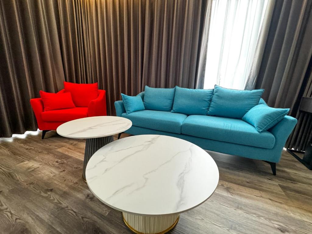 科隆Venus Royale Hotel的客厅配有蓝色的沙发和2把红色的椅子