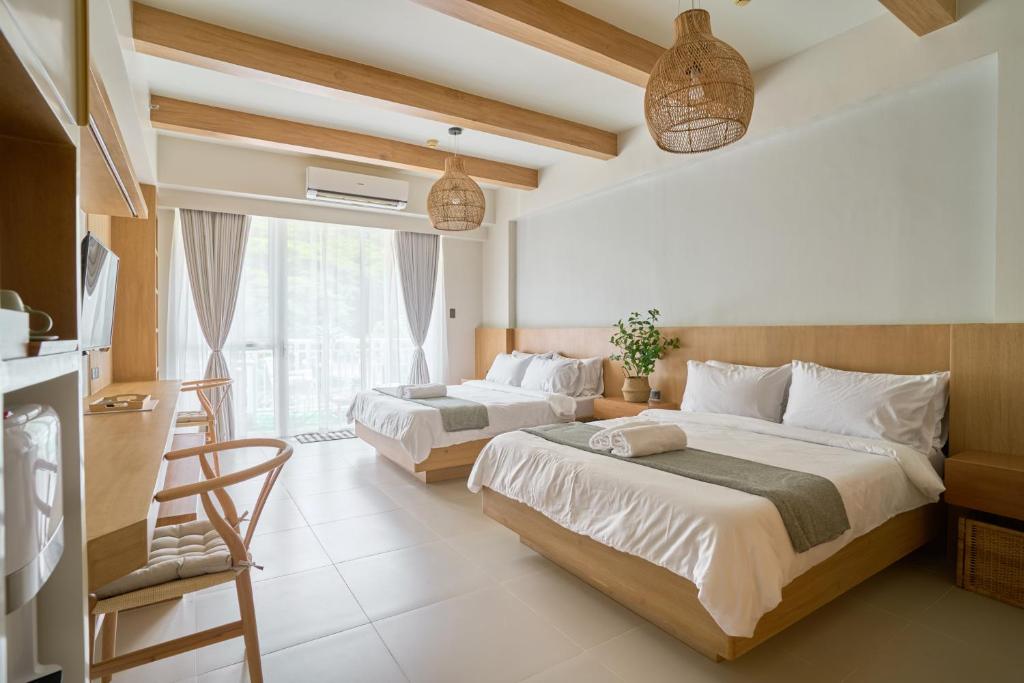 纳苏格布Yugen Suites 208 at Pico De Loro的一间卧室设有两张床和窗户。