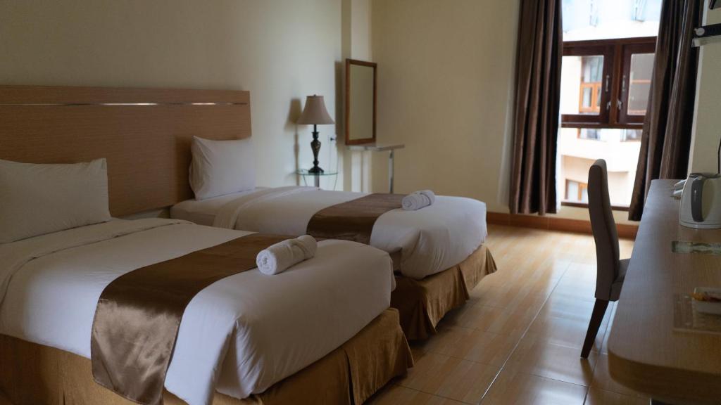 鲁滕Revayah Hotels的酒店客房设有三张床和窗户。