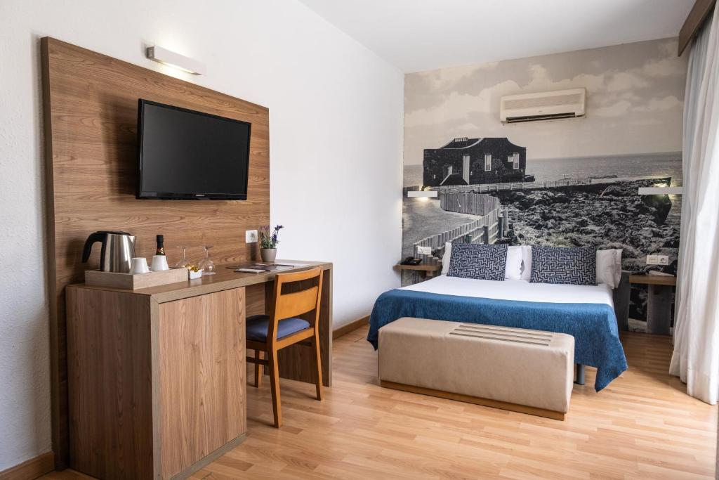圣克鲁斯-德特内里费阿多尼斯广场酒店的一间卧室配有一张床、一张书桌和一台电视。