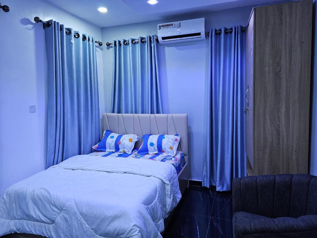 AgegeHEN - CAP SERVICED APARTMETS的一间卧室配有蓝色窗帘和一张带枕头的大床