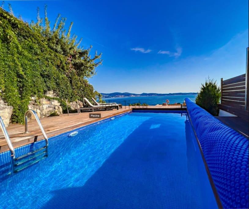 桑亨霍Villa mirador de Sanxenxo的蓝色的游泳池,设有木甲板和水