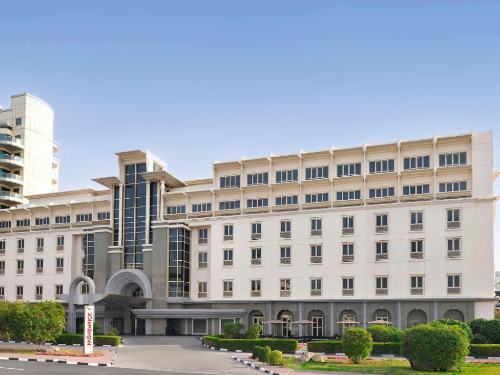 迪拜Mövenpick Hotel & Apartments Bur Dubai的一座白色的大建筑,有很多窗户