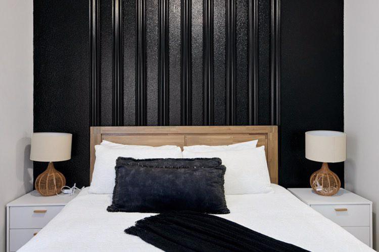 约翰内斯堡Sunrise Rivonia One Bed的一间卧室配有一张带黑色床头板的床和两盏灯。
