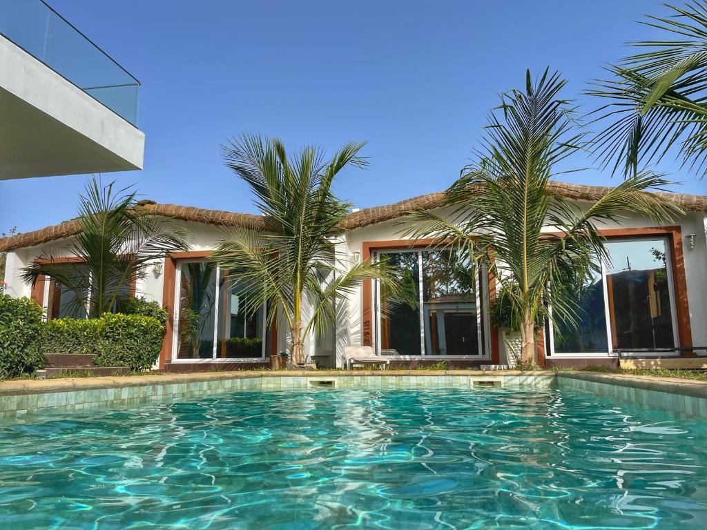 姆布尔Keur Ama的棕榈树屋前的游泳池
