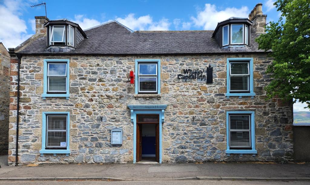 达夫敦Whisky Capital Inn的一座带蓝色窗户和门的古老石屋