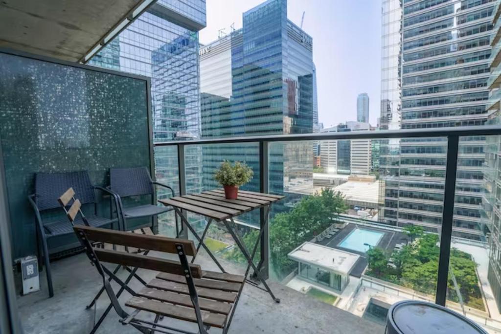 多伦多Simply Comfort Suites - One plus Den Apartment with Scotiabank Arena View的市景阳台配有桌椅。