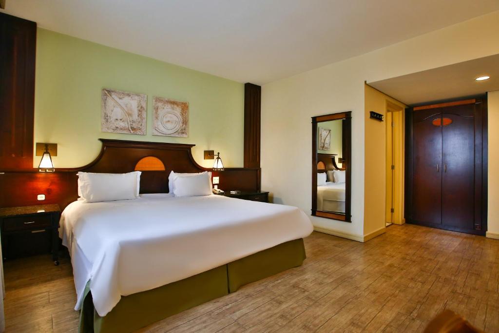 库里提巴库里提巴巴特尔全美高级酒店的卧室配有一张白色大床和镜子