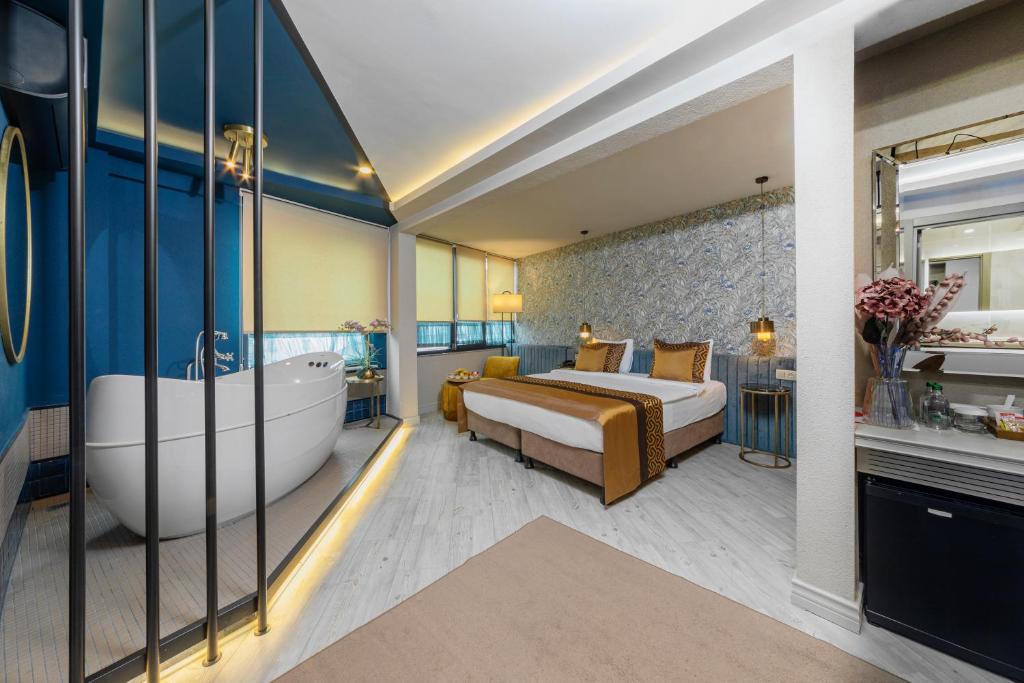 伊斯坦布尔Ayramin Deluxe Hotel Taksim的一间卧室设有一张大床和一个浴缸