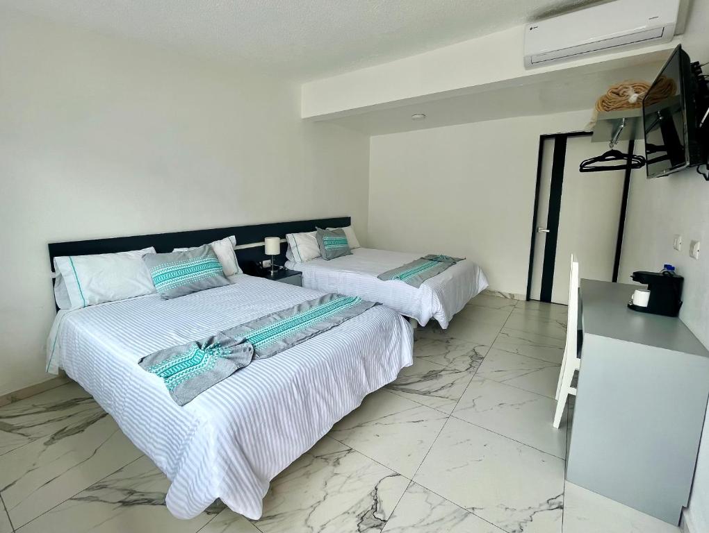 瓦哈卡市Villa Santa Julia的配有白色墙壁和大理石地板的客房内的两张床