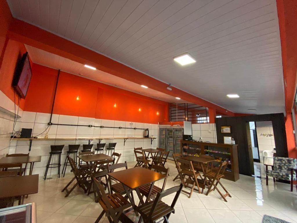 帕苏丰杜Pousada355的餐厅设有木桌和椅子,拥有橙色的墙壁
