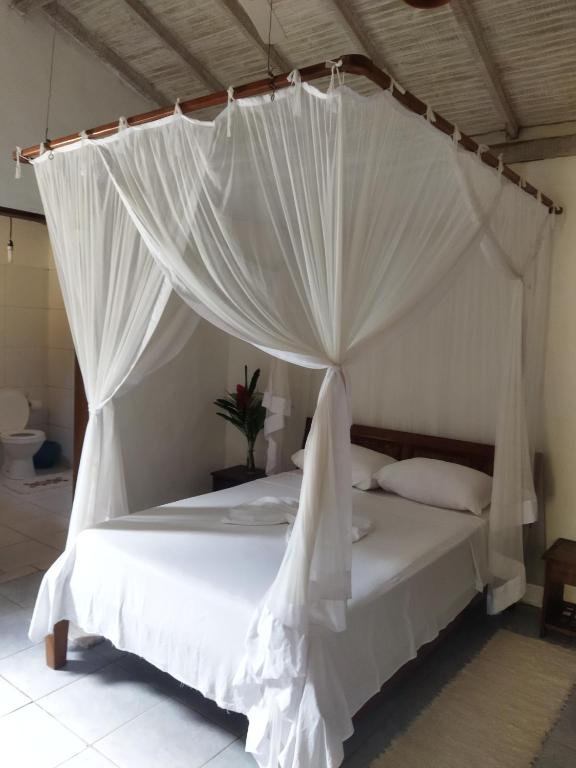 托兰克索Casa da Drica Trancoso的卧室配有带蚊帐的白色床