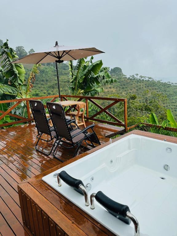 BuenavistaEco Glamping Cordillera的甲板上的热水浴池配有椅子和遮阳伞