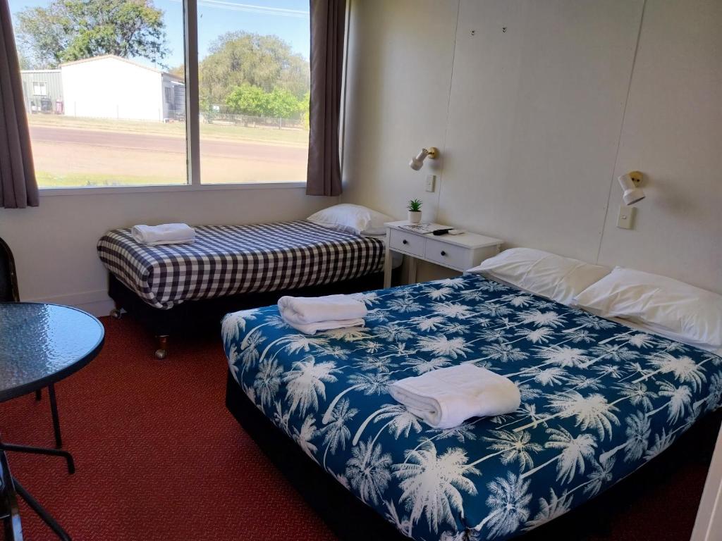 布莱克尔Motel Blackall的客房设有两张床、一张桌子和一扇窗户。