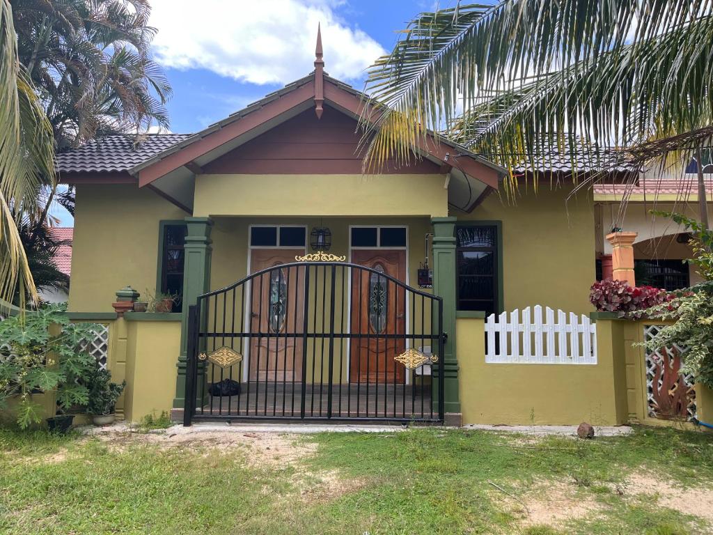 瓜拉丁加奴HIJRAH FLEKSI HOMESTAY的黄色的房子,有门和栅栏