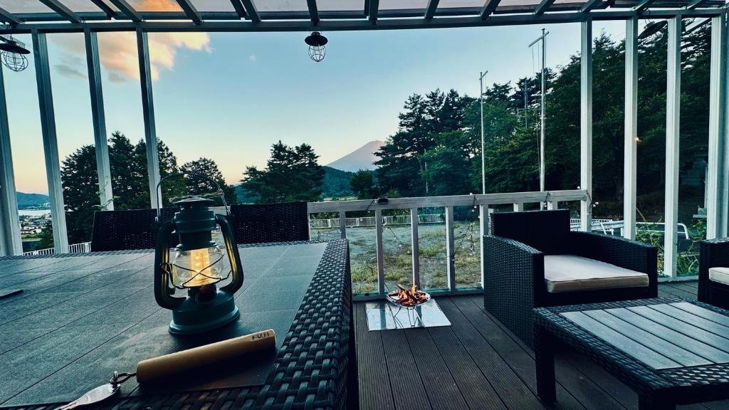 富士河口湖glampark S.O.P Fuji Kawaguchi Lake的阳台配有桌子、灯和椅子