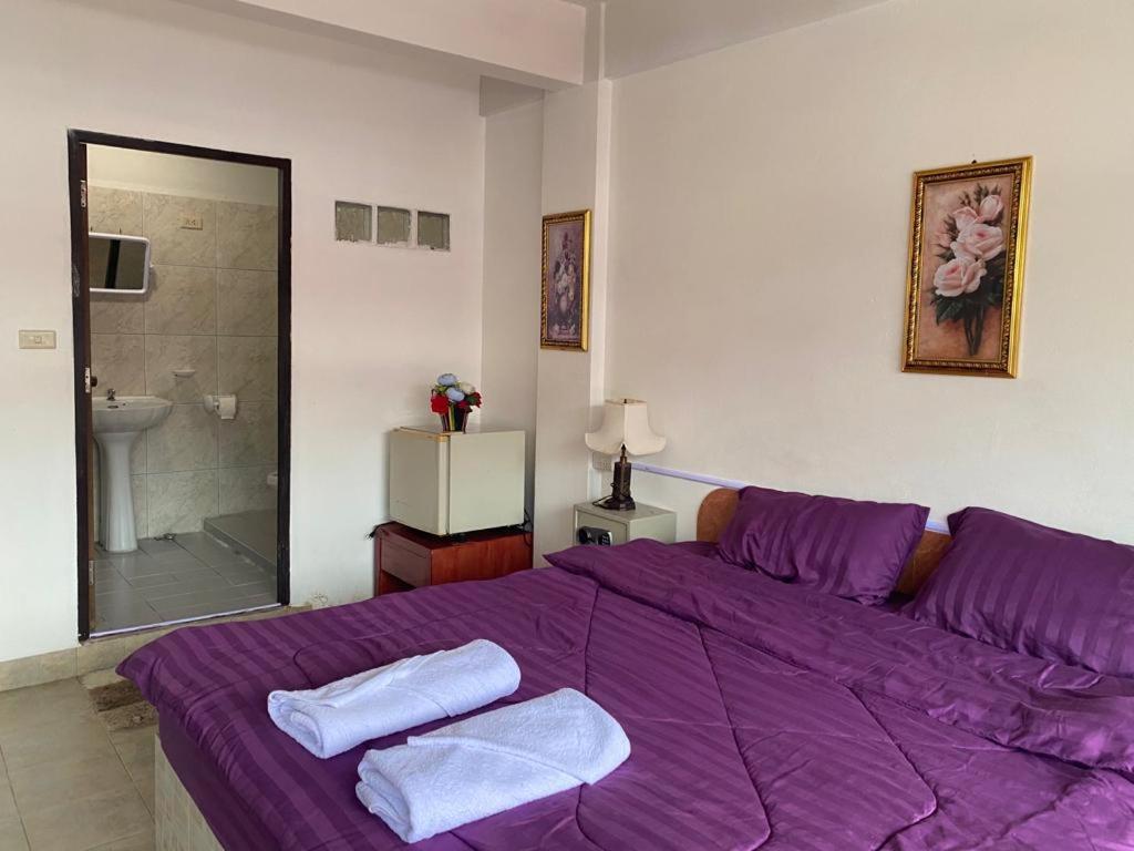 乔木提恩海滩Chai Ben guesthouse的一间卧室配有一张紫色床和毛巾