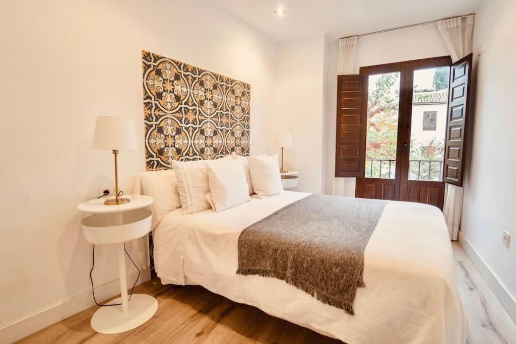 格拉纳达Torre de la Vela 1的白色的卧室设有一张大床和一个窗户