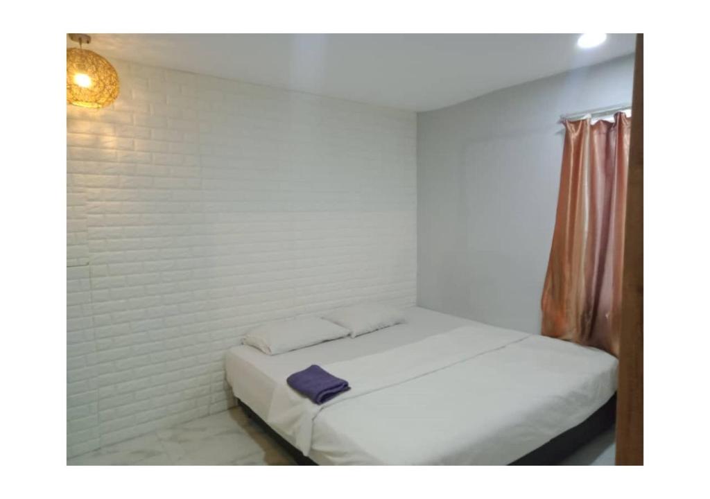 吉隆坡EXPRESS OYO HOTEL的白色卧室,配有一张带紫色毛巾的床