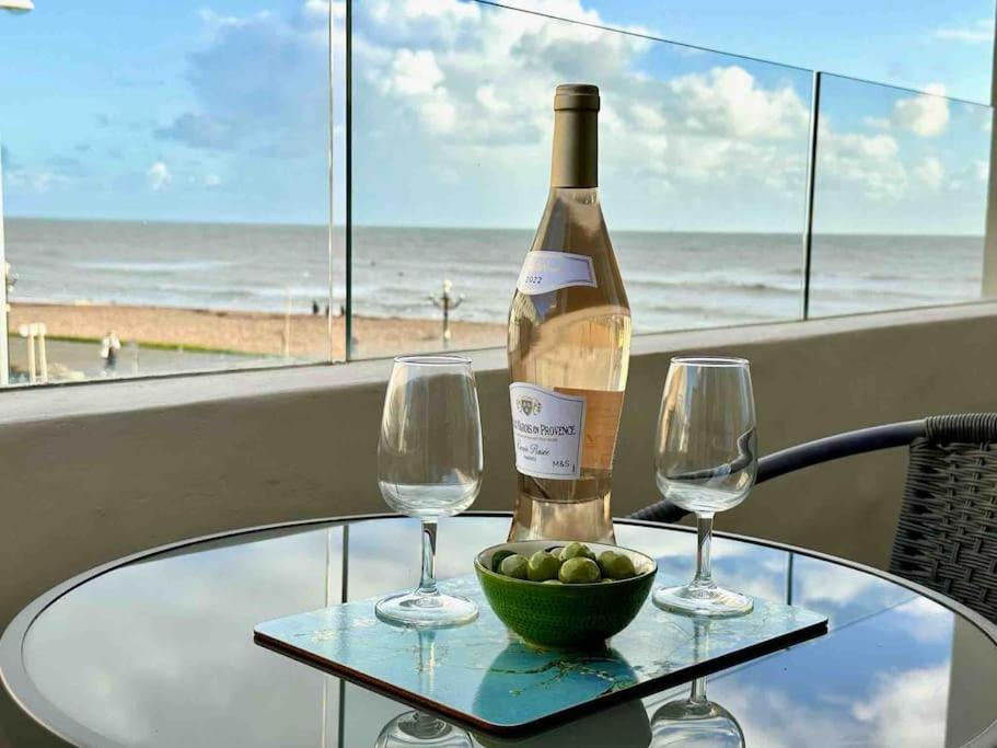 沃辛House by the Sea, Worthing的一张桌子上放着一瓶葡萄酒,放上两杯