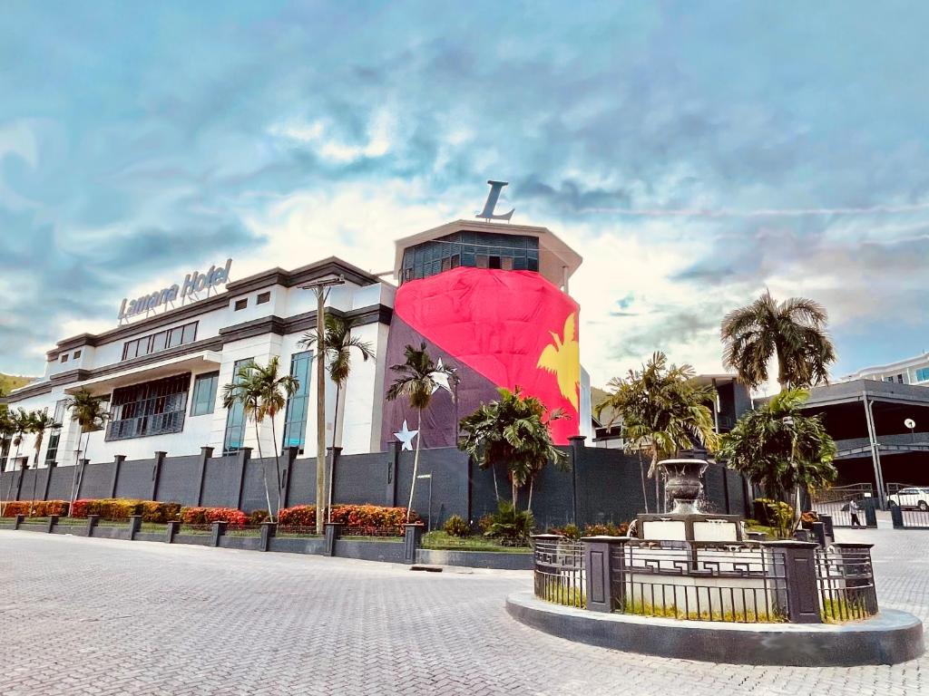 莫尔兹比港拉马纳酒店 的前面有粉红色伞的建筑
