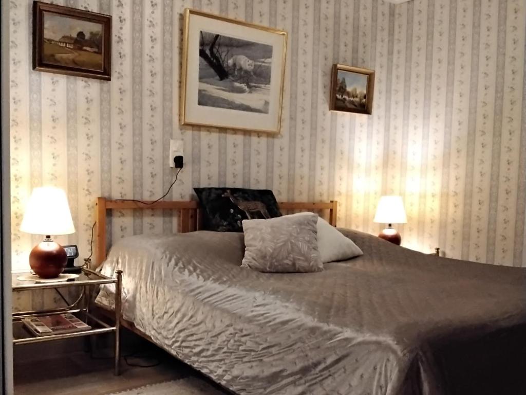 特雷勒堡Bo i Trelleborg的一间卧室配有一张带两盏灯的床,墙上有两张照片
