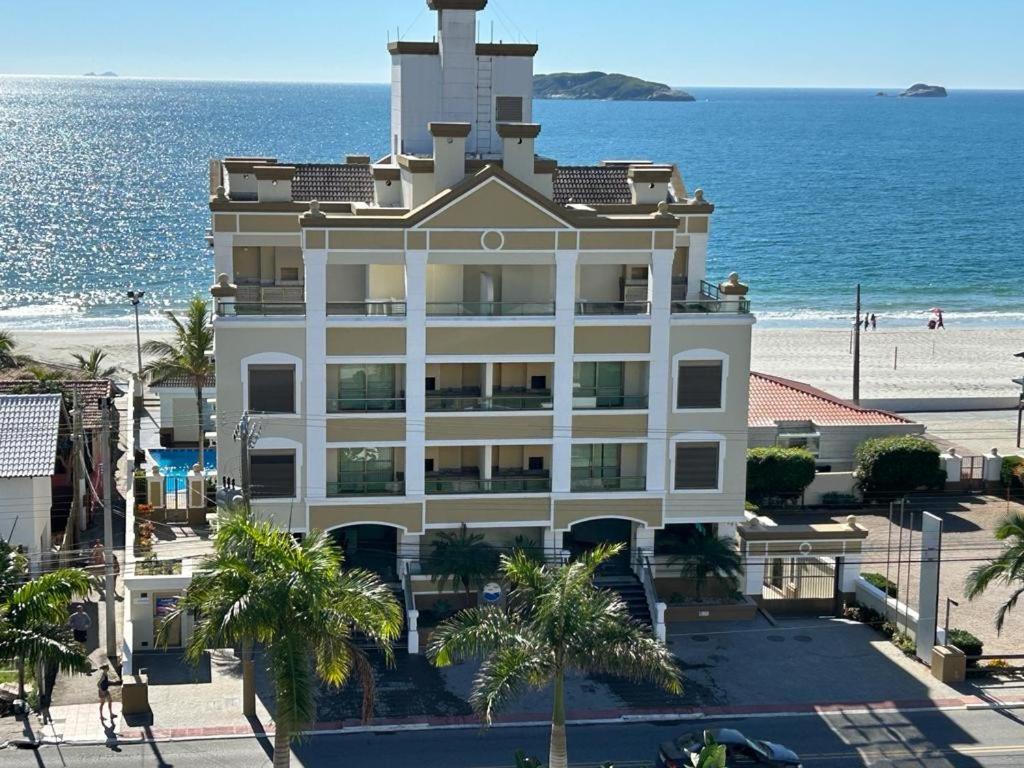 弗洛里亚诺波利斯Golfinhos ApartHotel a beira-mar!!的海滩上的建筑,以海洋为背景