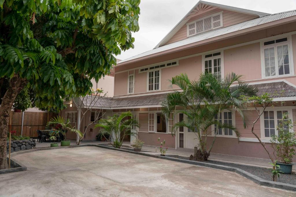帕皮提La Maison de Paofai的一座大粉色房子前面有树木