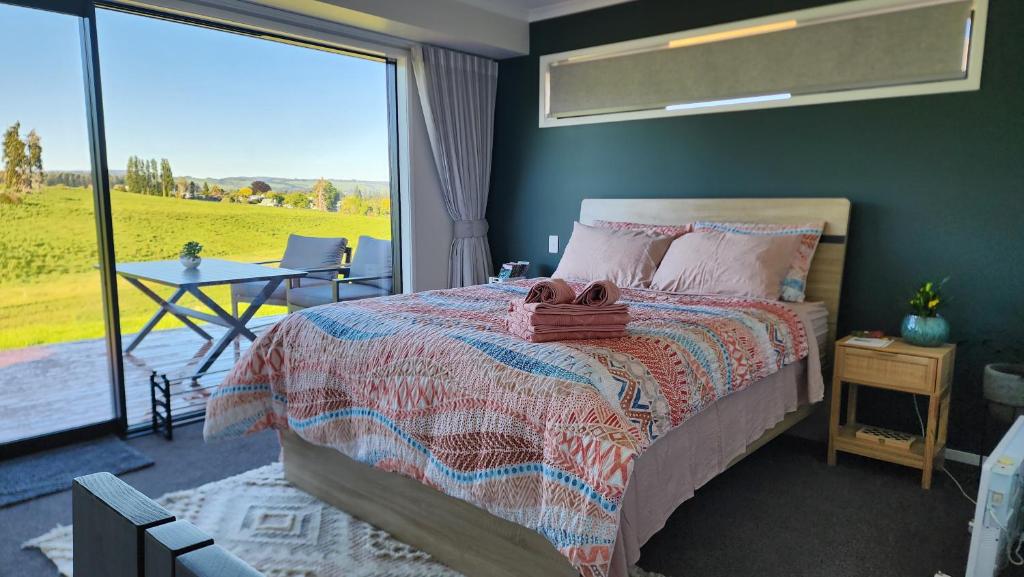 罗托鲁瓦A stunning retreat in Rotorua!的一间卧室配有一张床、一张桌子和一个大窗户