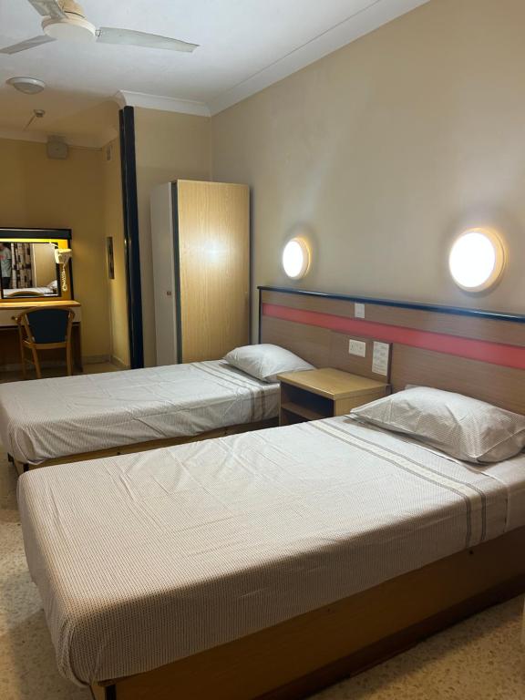 圣朱利安斯EA holiday beds的两张床铺,位于酒店客房,墙上有灯