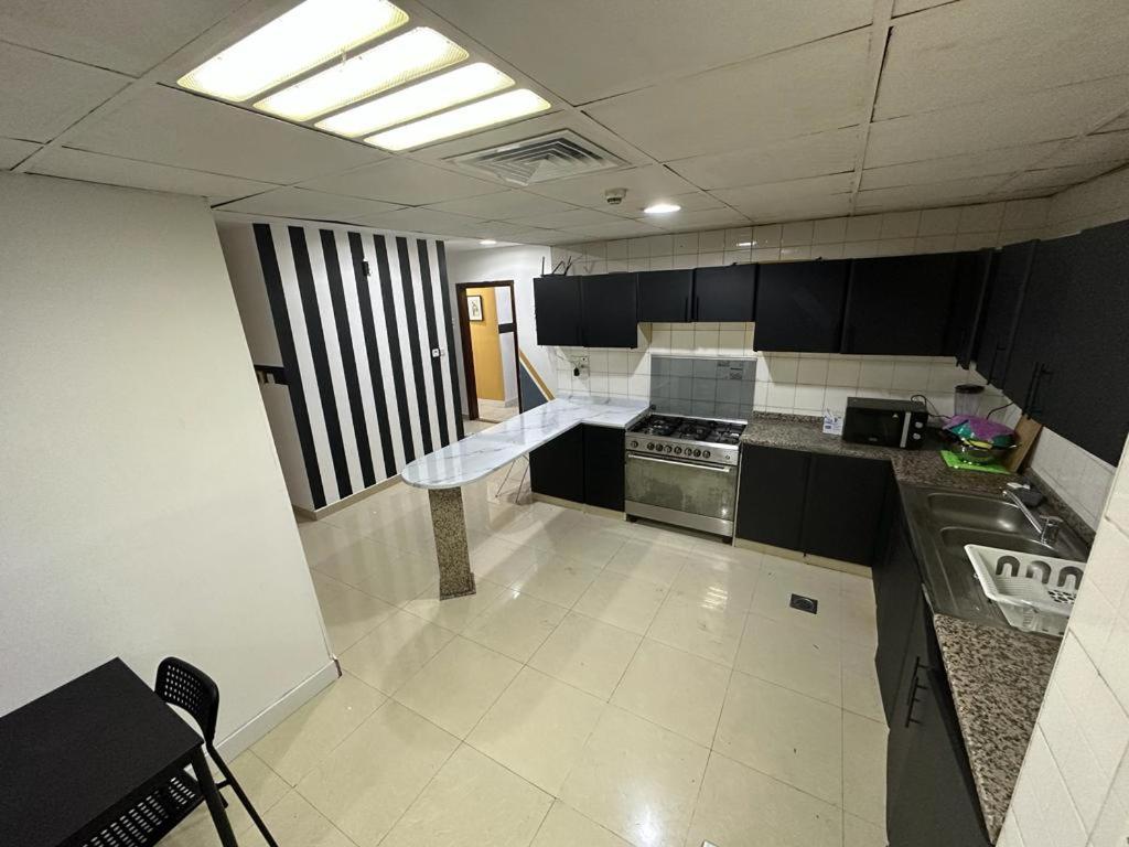 迪拜Short Stay Partition Room in Al Barsha 1 Near Mashreq Metro的厨房配有黑白橱柜和炉灶。