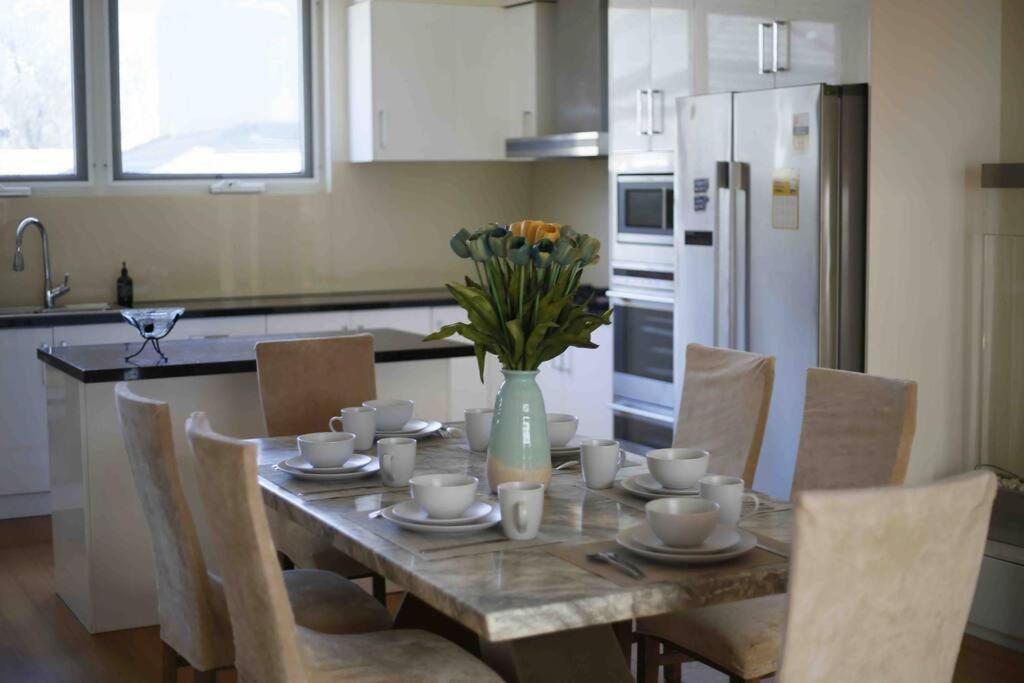 伯伍德Perfectly modern living home in Burwood的厨房配有一张桌子,上面放着花瓶