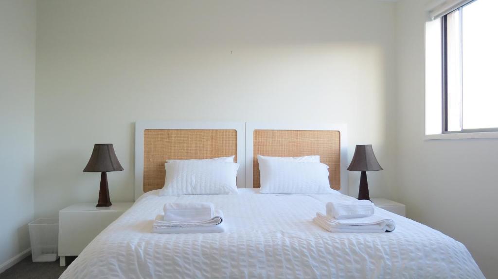 TuggeranongGREENWAY WATERS Apartments的卧室配有白色的床和2条毛巾