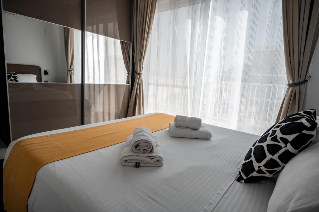 维多利亚Cittadella View Penthouse with Jacuzzi的一间卧室配有带毛巾的床和窗户。