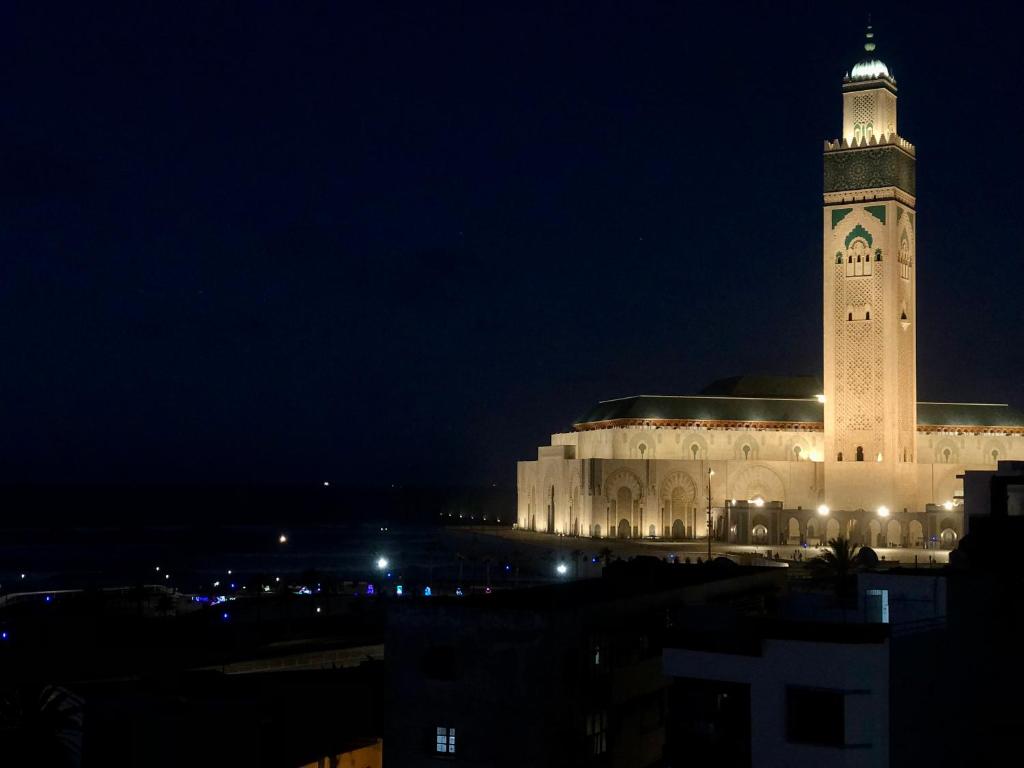 卡萨布兰卡Bel appartement avec une belle vue sur la grande mosquée Hassan II et la mer的一座在晚上设有钟楼的大型建筑
