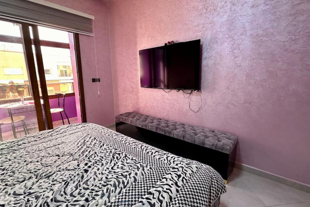 梅克内斯appartement tout confort的卧室配有一张床,墙上配有电视。