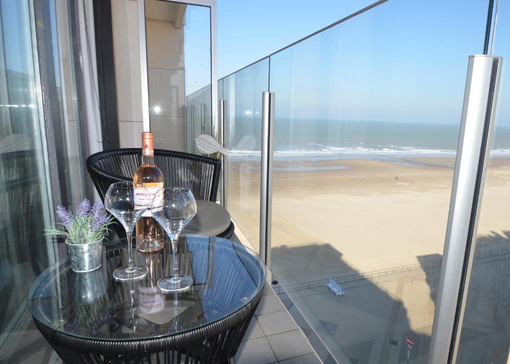米德尔克尔克An's seaview Middelkerke的阳台上的桌子上摆放着玻璃杯和一瓶葡萄酒