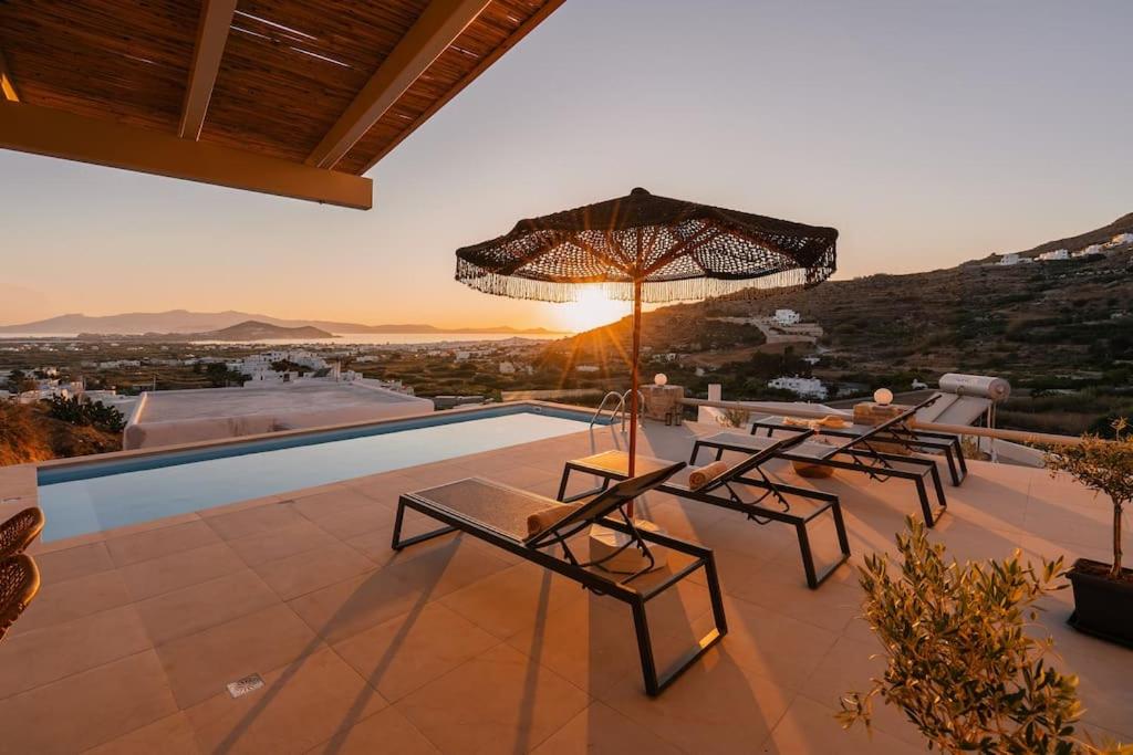 AgkidiaPleiades Villas Naxos2 (Hottub)的一个带桌子和遮阳伞的庭院和一个游泳池
