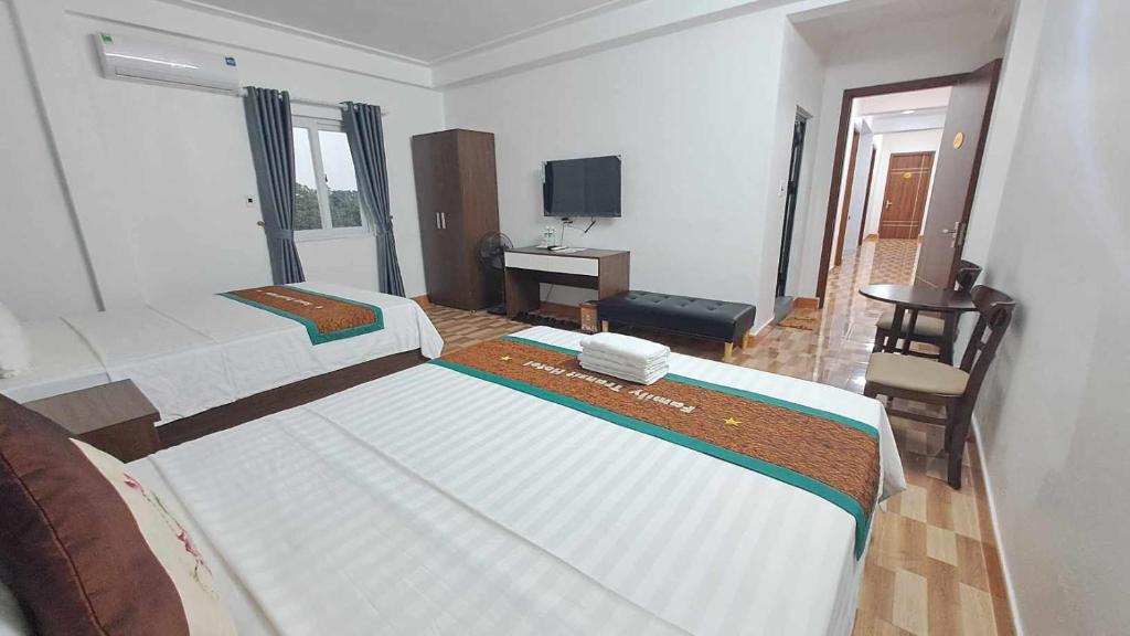 Thach Loi家庭过境酒店的一间卧室配有两张床、一张桌子和一台电视。