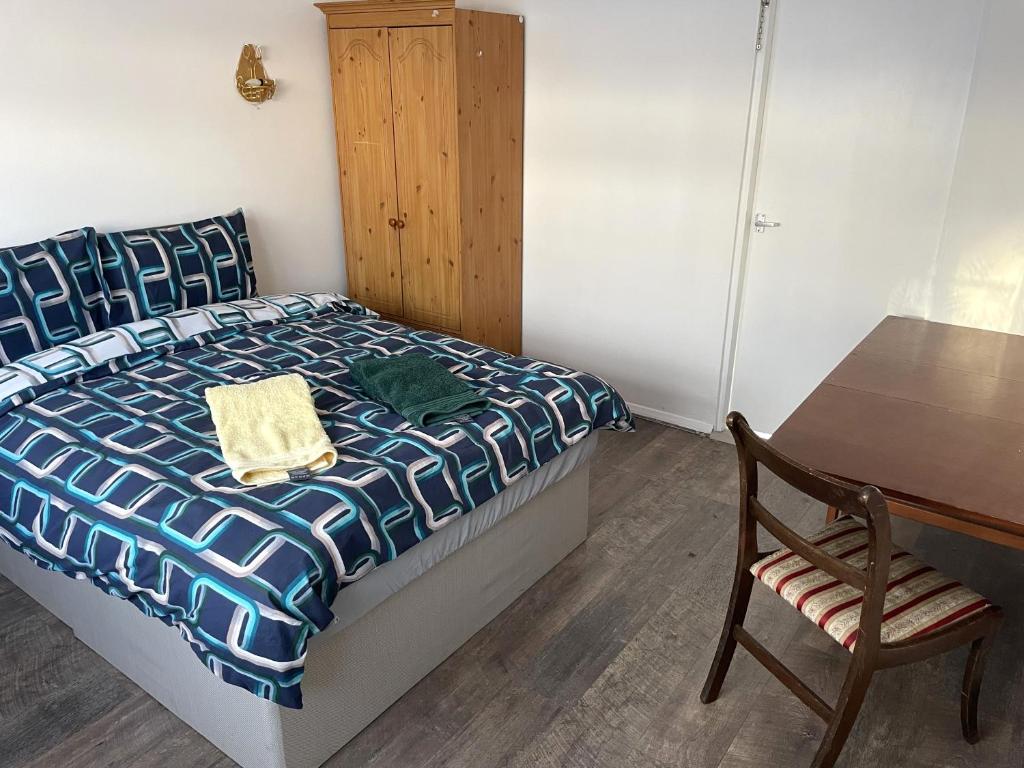 埃尔特姆A nice double bedroom in Mottingham的一间卧室配有一张床、一张桌子和一把椅子