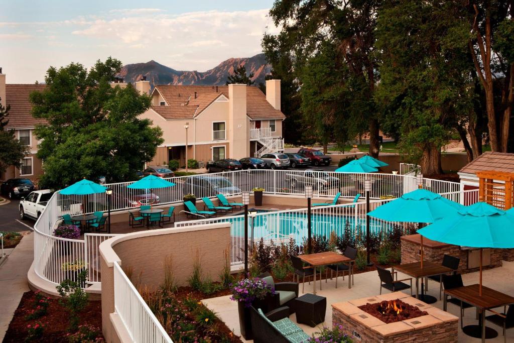 博尔德Residence Inn by Marriott Boulder的一个带桌椅和蓝伞的游泳池