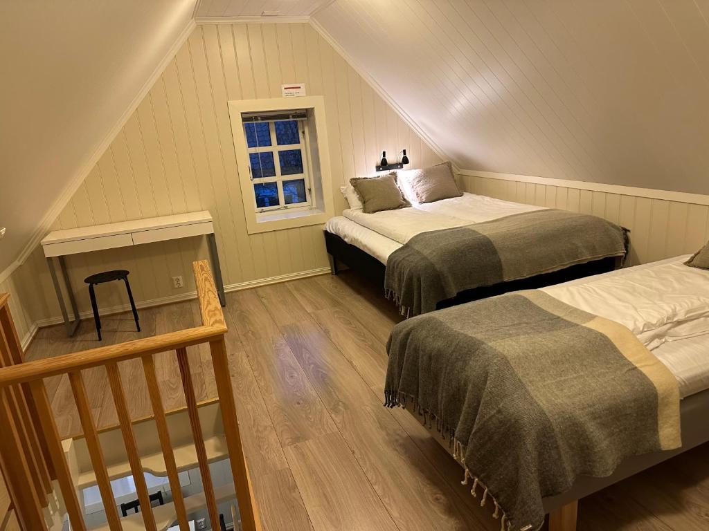 拉尔维克Tollgaarden Gjestegaard的阁楼卧室设有两张床和窗户。