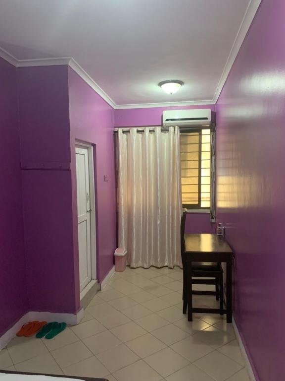 达累斯萨拉姆Kibodya Hotel Nkrumah的一间拥有紫色墙壁、一张桌子和一把椅子的客房