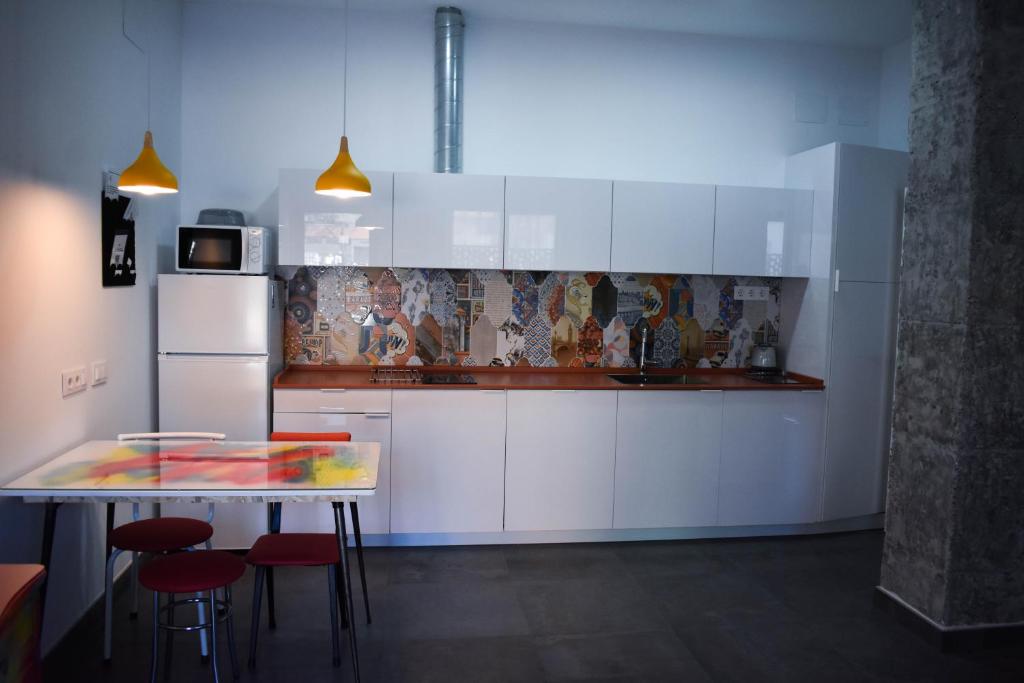 塞维利亚Sevilla Urban Flat的厨房配有白色橱柜和带凳子的桌子