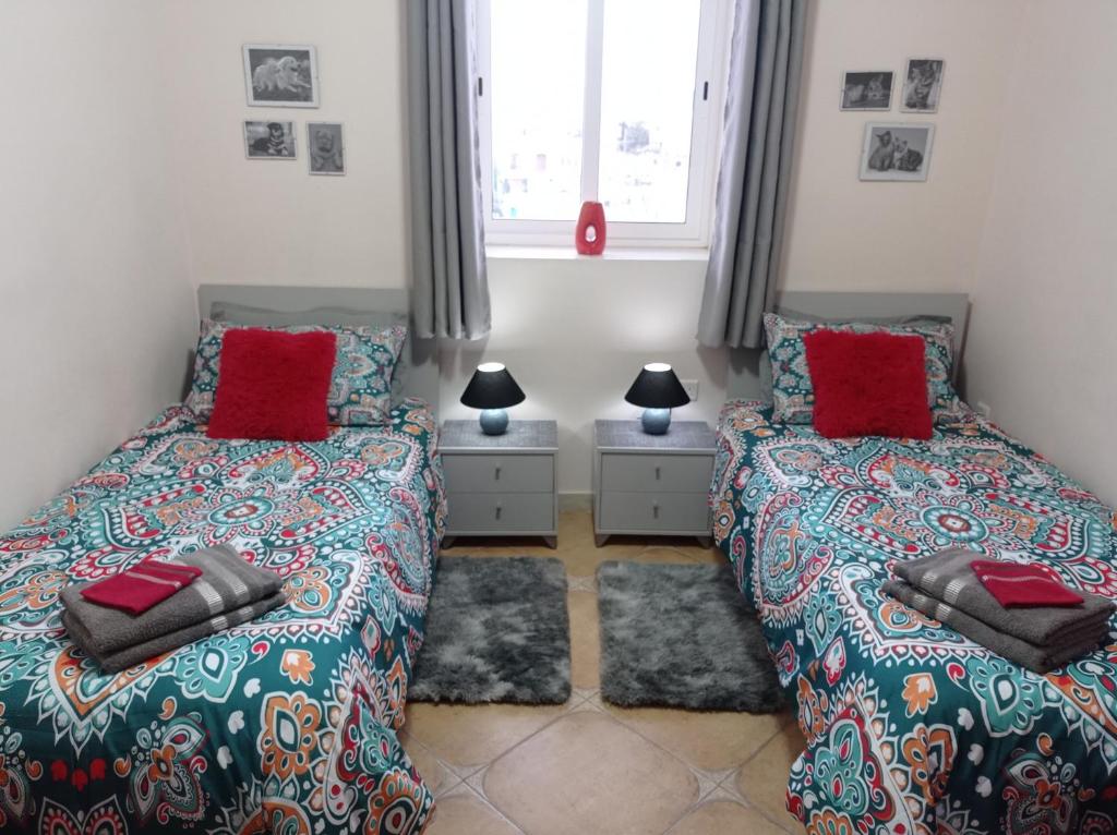Siġġiewi"Joseph 2" Stylish corner flat with open views, just 5km from the beach的一间卧室配有两张带红色枕头的床