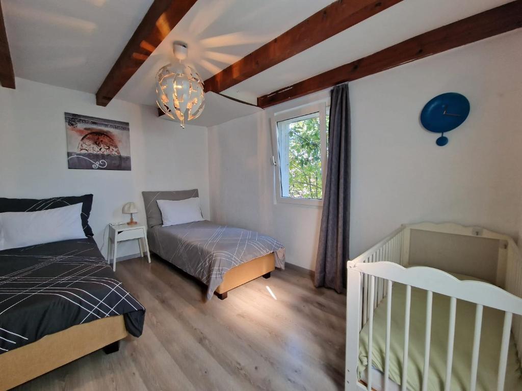 CollombeyMaison villageoise的一间卧室设有两张床、一张婴儿床和一扇窗户。